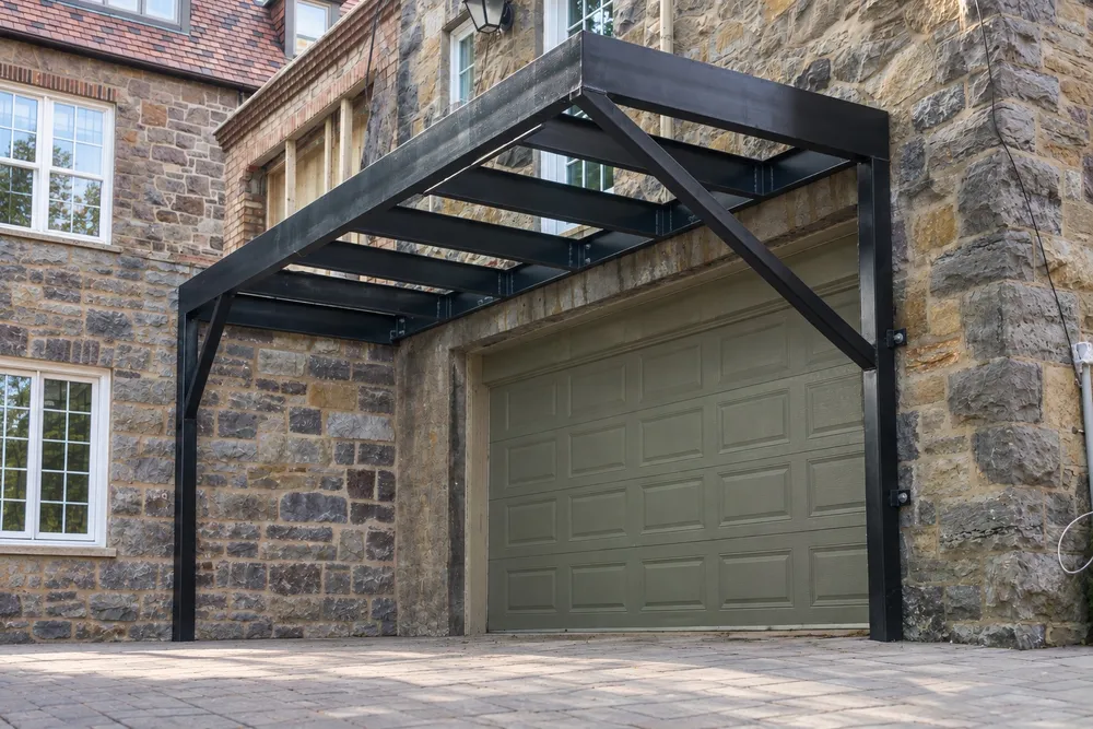 Structure en acier noir ancrée à la façade d’une maison en pierre